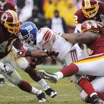 Giants running back Derrick Ward carries the ball through Washington Redskins safety Chris Horton (48), linebacker Rocky McIntosh, and defensive tackle Anthony Montgomery.